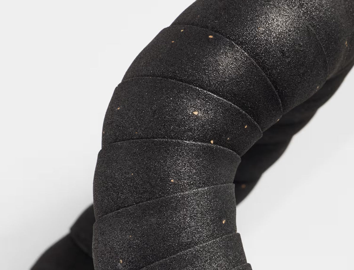 Close up of Trek black gel cork bicycle handlebar tape installed on a handlebar on a white background.