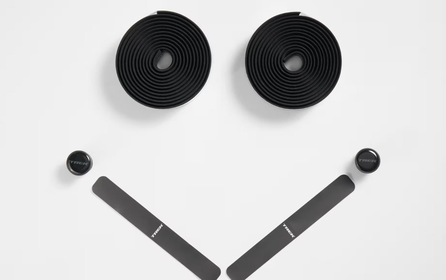 Two rolls of black Trek gel cork bicycle handlebar tape, two black bar end plugs, and two strips of Trek branded finishing tape on a white background.
