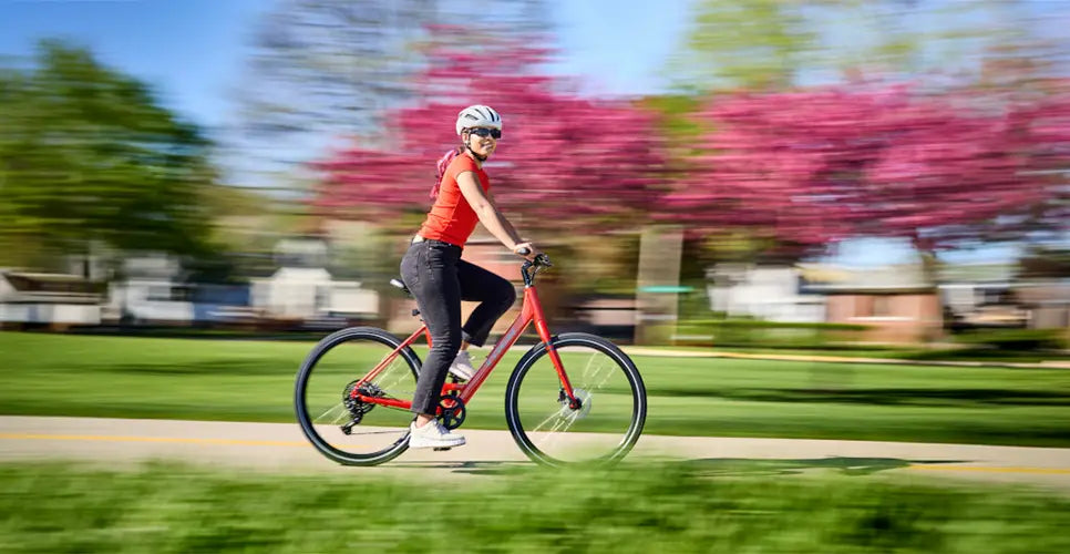 A woman rides a Trek bicycle through a neighborhood in spring.