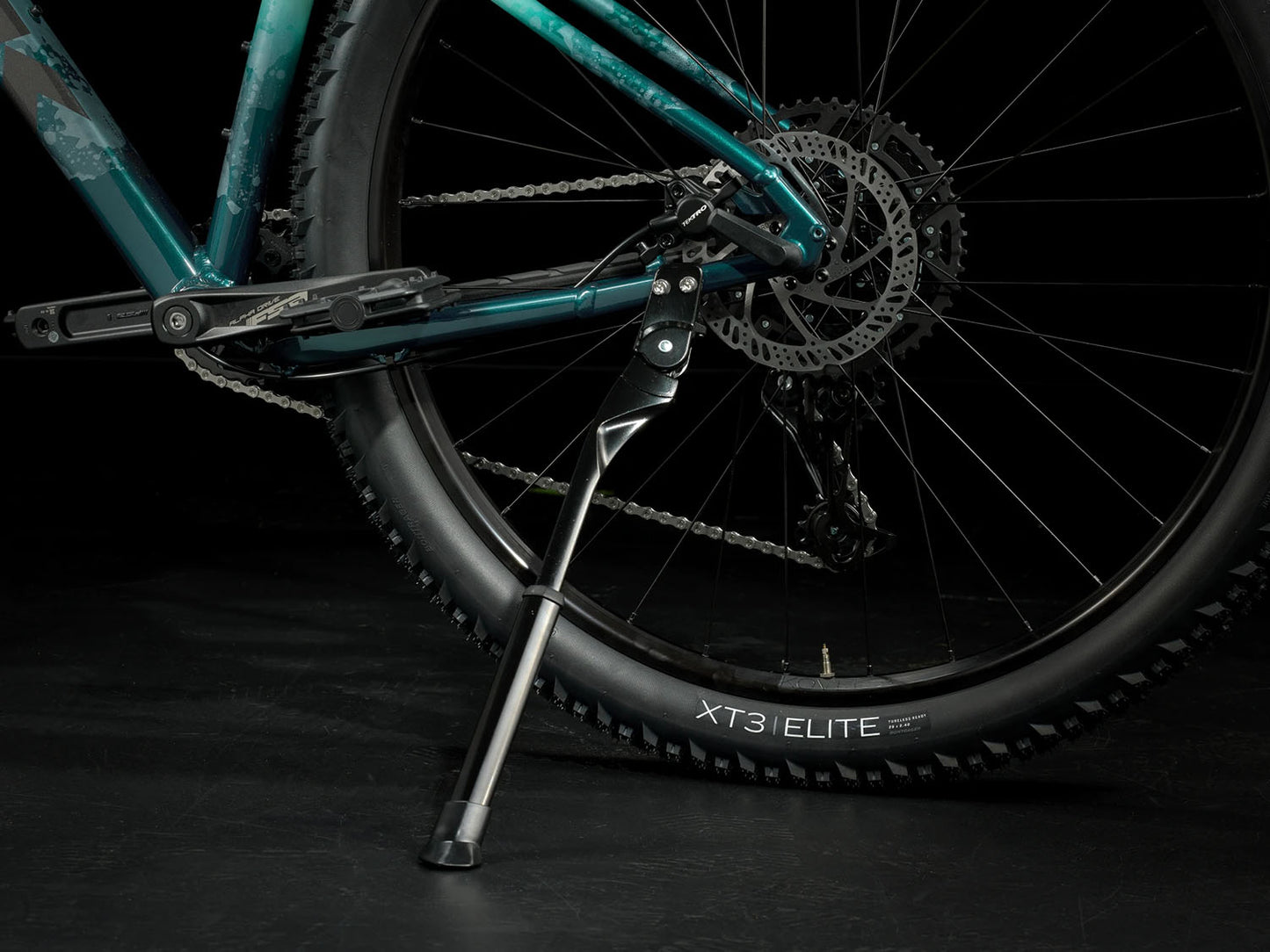 A closeup view of the kickstand of the Trek Marlin 6 Gen 3 mountain bike in Miami Green to Dark Aquatic Fade against a black background.