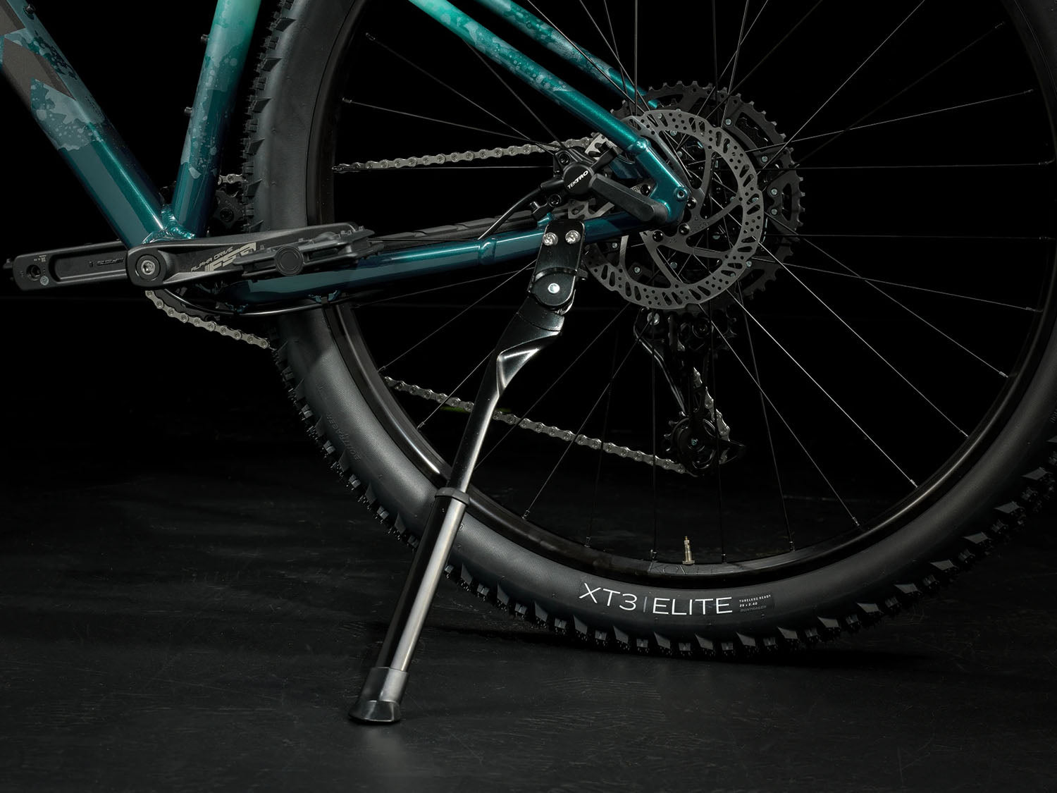 A closeup view of the kickstand of the Trek Marlin 6 Gen 3 mountain bike in Miami Green to Dark Aquatic Fade against a black background.