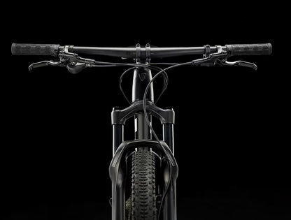 Black Trek Procaliber 6 bicycle with handlebars and front wheel on a black background.