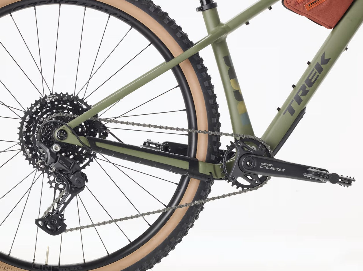 Close-up of a matte olive Trek Roscoe 7 bicycle wheel and gear system with charcoal 'Trek' branding on a white background.