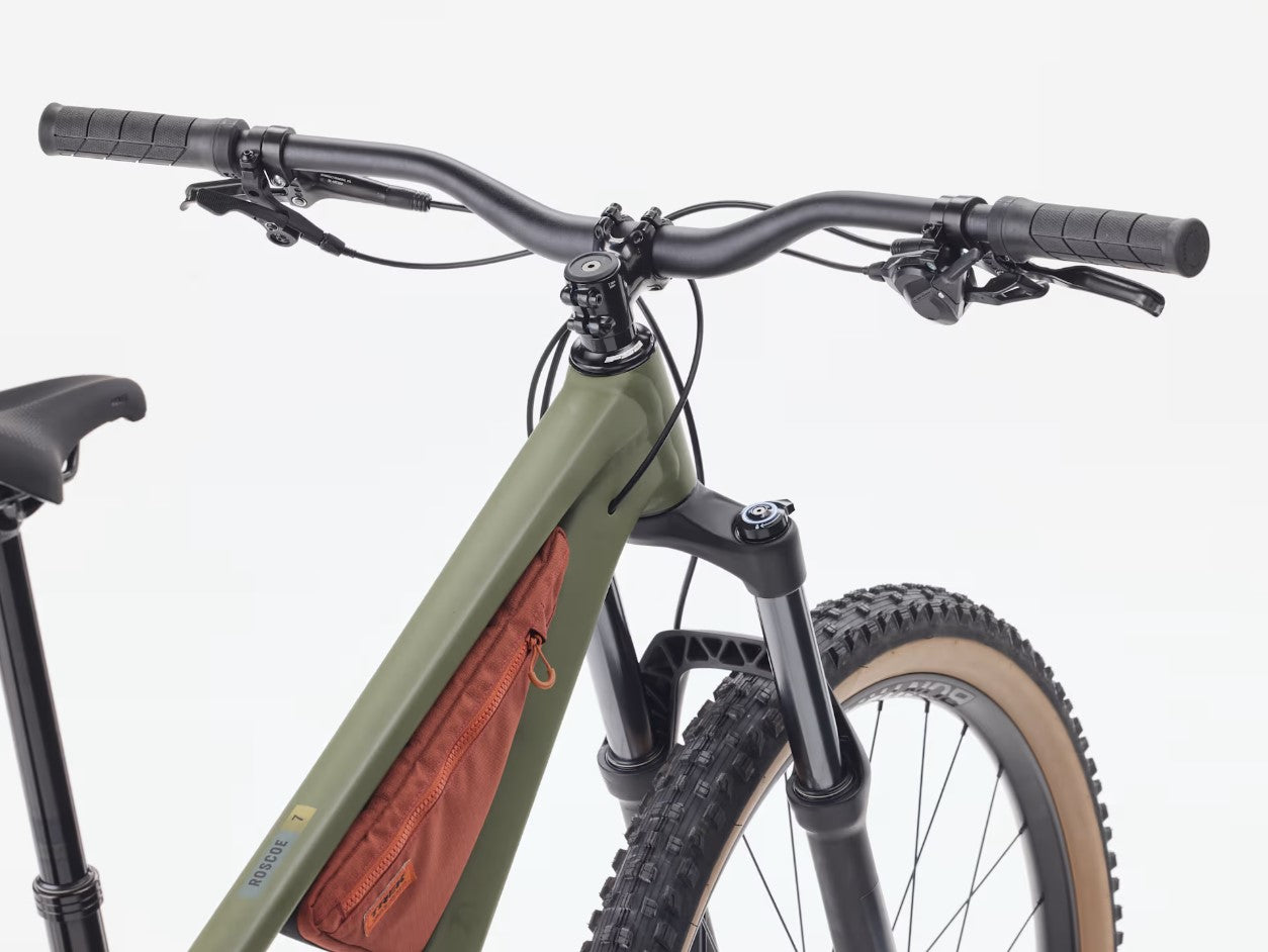 Close-up of the handlebars of a matte olive Trek Roscoe bicycle with a white background.