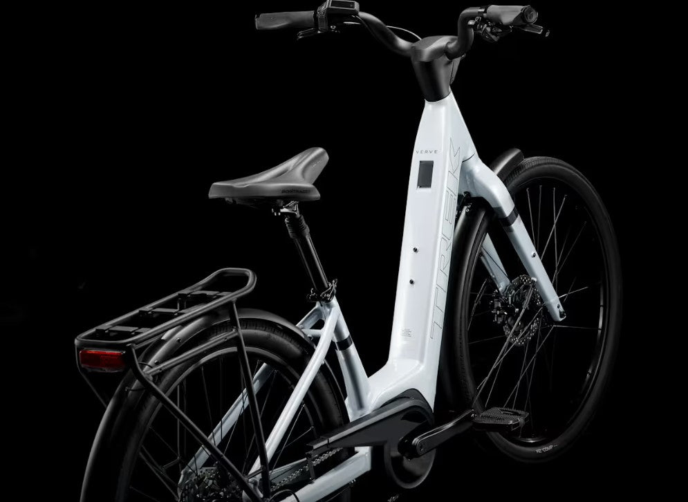 White Trek Verve Plus electric bike with black seat and rear rack on a black background
