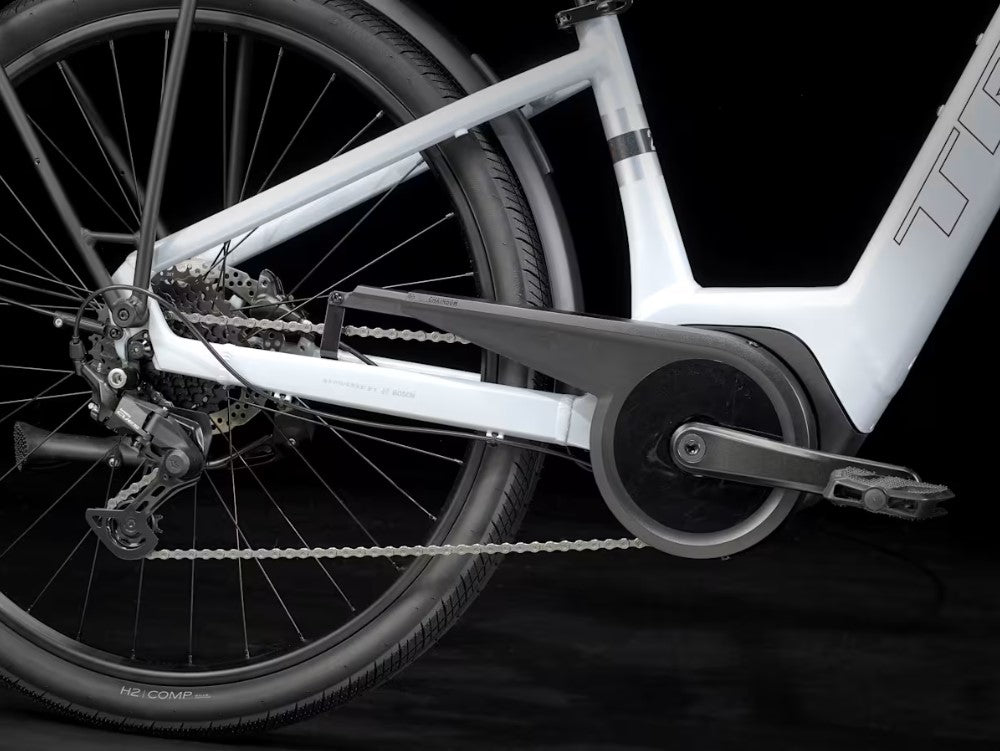 Close-up of a white Trek Verve Plus bicycle's chain and gear system on a black background