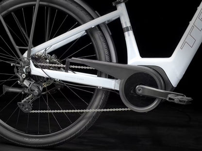 Close-up of a white Trek Verve Plus bicycle's chain and gear system on a black background