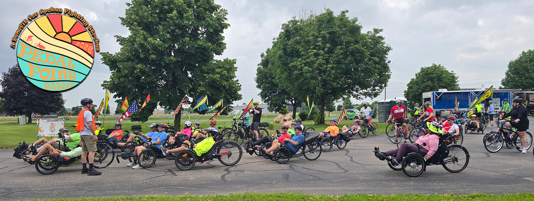 Riders get ready to participate in the Pedal Point Rally bike tour on a cloudy day in 2025. A colorful 2026 Pedal Point Rally logo is in the corner.