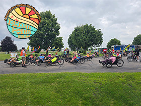 Riders get ready to participate in the Pedal Point Rally bike tour on a cloudy day in 2025. A colorful 2026 Pedal Point Rally logo is in the corner.