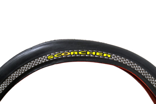 A close-up image of a Greenspeed Scorcher folding bike tire with a red Kevlar bead and checkered flag sidewall pattern.