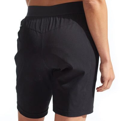 A pair of black Pearl Izumi women's cycling shorts with a wide stretch waistband and hand pockets on a model