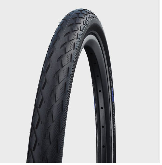 A black Schwalbe Marathon GreenGuard bicycle tire with a herringbone tread pattern, wired bead design, and visible blue reinforcement layer.