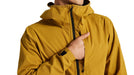 Specialized Trail rain jacket in harvest gold. Jacket has a black zipper and chest pocket and hood.  Hood is lowered on model in photo.