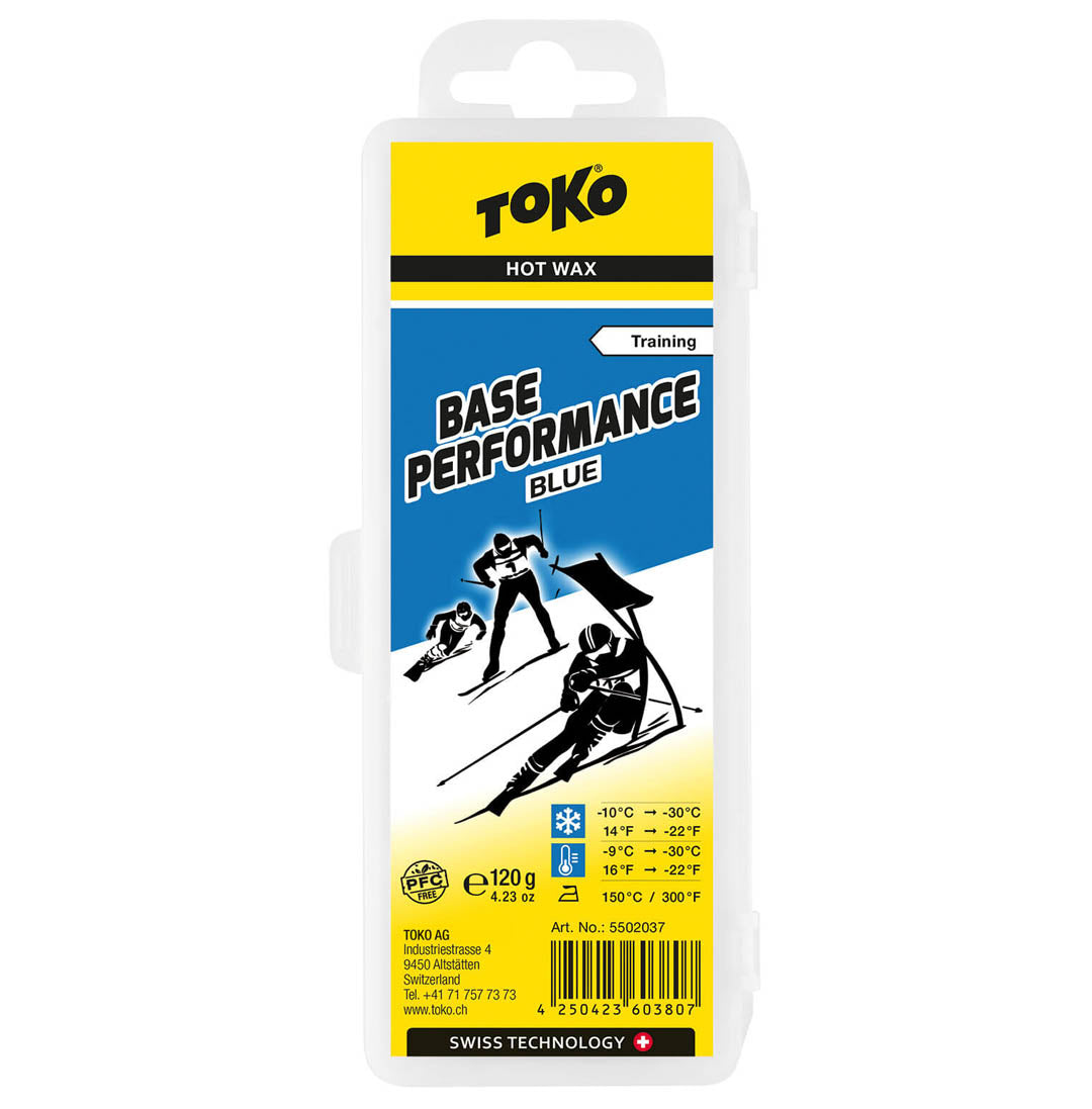 Package of Toko Performance Blue base wax.  Package is mostly yellow, with image of 3 black and white skiers, blue sky and white snow.  Black lettering on front of package.