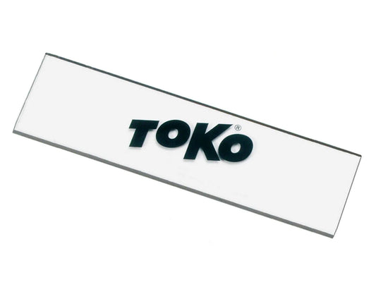 A white snowboard scraper with the brand name 'TOKO' printed in black lettering.