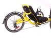 Rear half profile studio view of a Catrike Trail recumbent trike with a yellow frame, black seat pad, 20 inch wheels and a black rear fender.