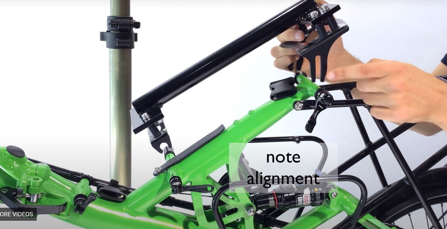 View of the HP Velotechnik Scorpion Assembly Mount Workstand Bracket getting attached to a green recumbent bike against a white background.