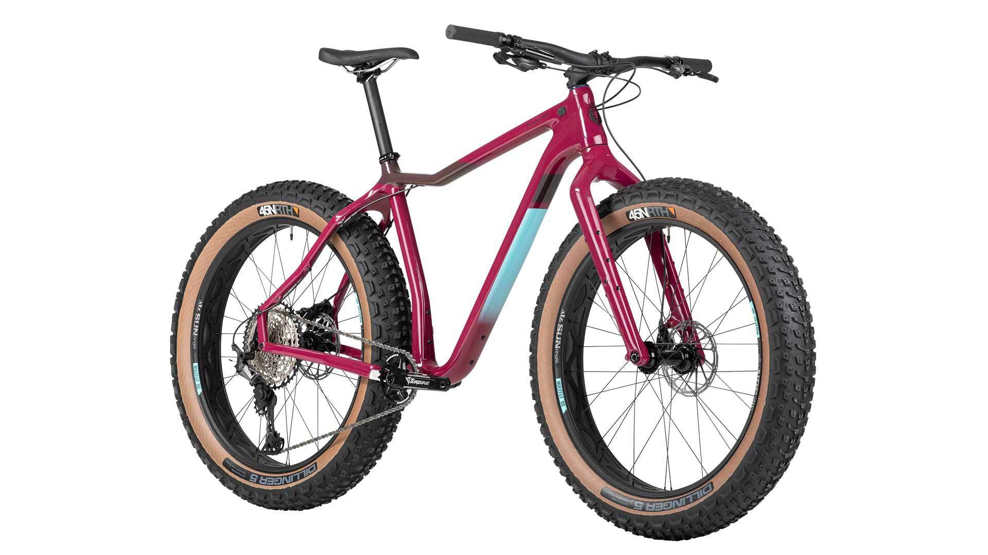 Front right angled profile view of a purple Salsa Mukluk fat bike with black and blue accents and tan sidewall tires on a white background. 