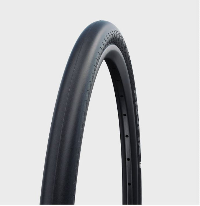 studio view of half of a Schwalbe Kojak black bicycle tire installed on a black rim showing smooth tread of tire