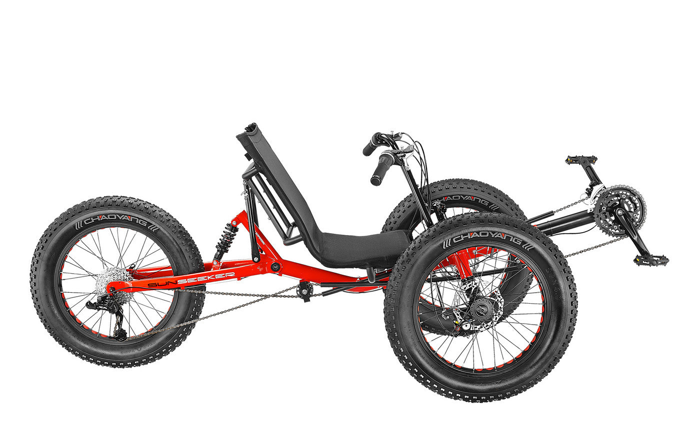 A red recumbent trike with fat tires designed for off road use, featuring a black seat and frame details.