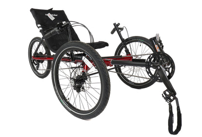 Angled view of a red and black TerraTrike Traveler recumbent trike with a black seat and folding handlebars, equipped with a chain drive and mechanical disc brakes.