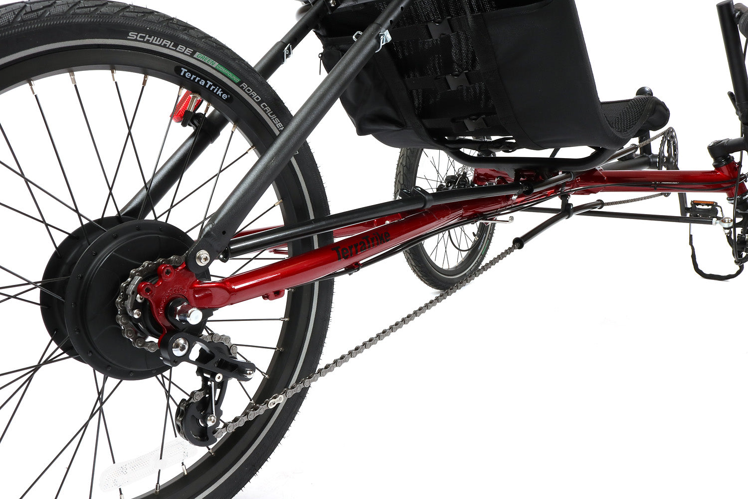 Closeup view of a red and black TerraTrike Traveler recumbent trike with a black seat and folding handlebars, equipped with a chain drive and mechanical disc brakes.