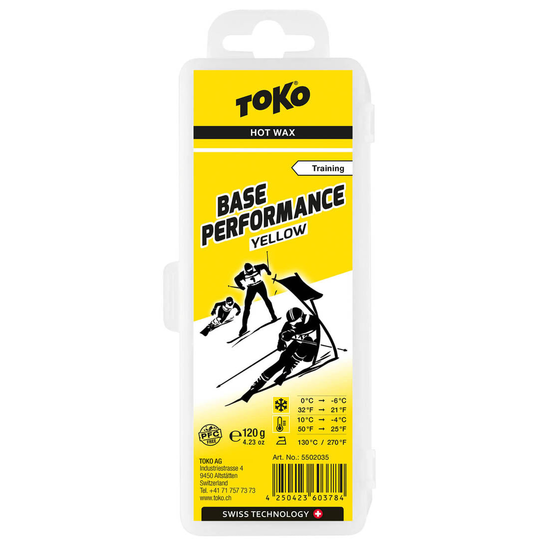 Front view of packaging for Toko Performance Yellow Base wax. Package is mostly yellow with black lettering and 3 black and white skiers.